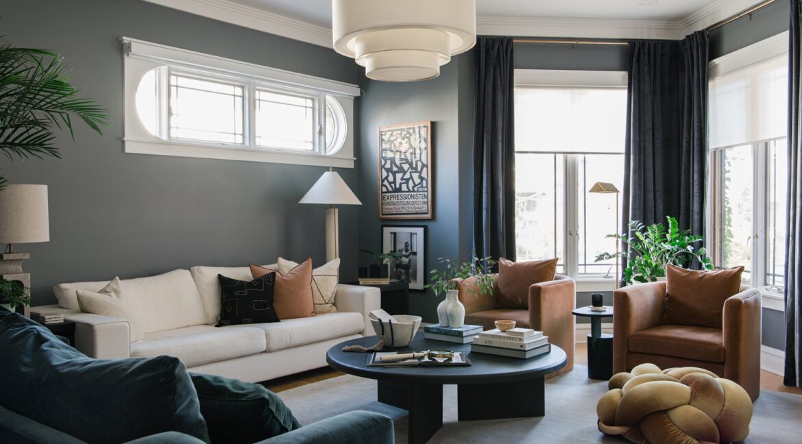Blog post features image of Candace Mary Interiors space. Room is a moody slate blue painted walls, with a cream, and blue sofa and cognac accent chairs.